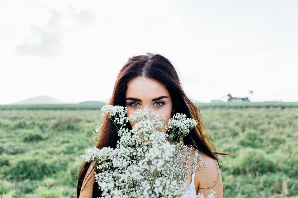 Young woman in field holding flowers